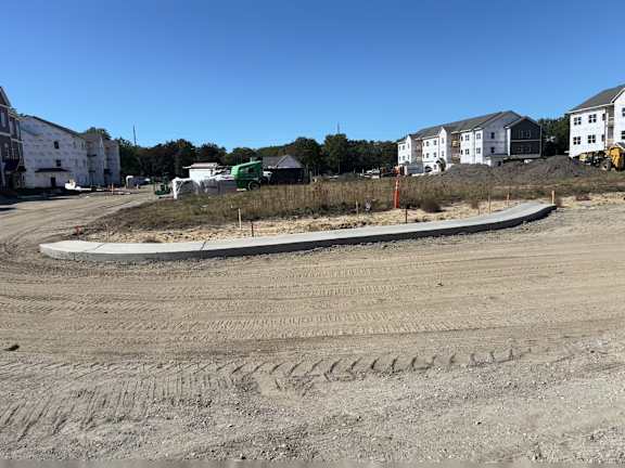 A construction site with a large white building in the background.