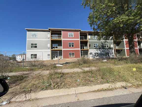 A multi-story apartment building with a mix of grey, red, and white exterior colors.