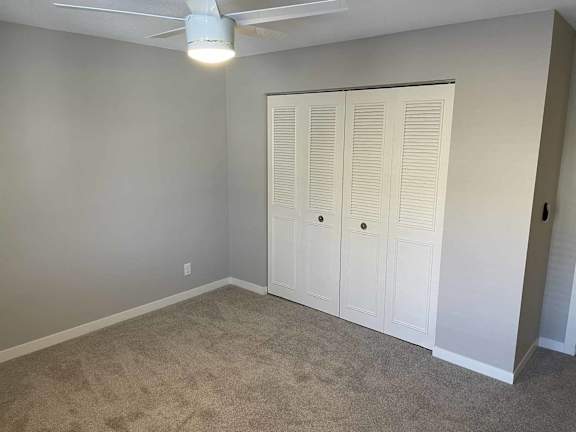 A room with a white closet and carpeted floor.