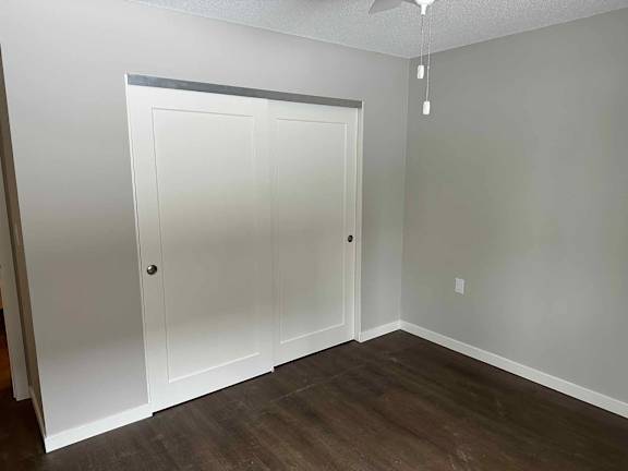 A room with a white door and a ceiling fan.