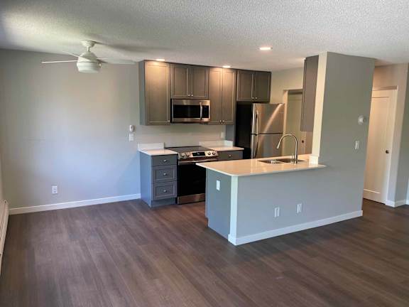 A kitchen with a refrigerator, microwave, and oven.