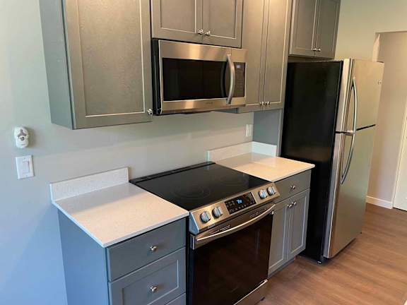 A kitchen with a black stove top oven and a black refrigerator.