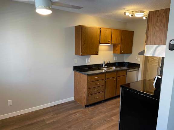 A kitchen with wooden cabinets and a black countertop.
