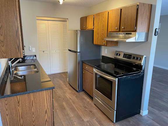 A kitchen with a black countertop and stainless steel appliances.