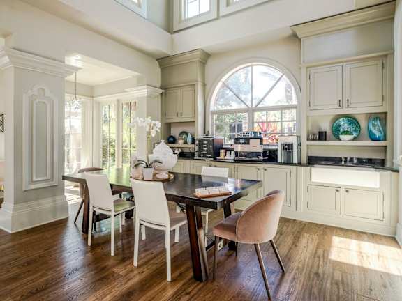 Resident coffee bar and dining space featuring custom cabinetry, espresso machine, and warm daylight.