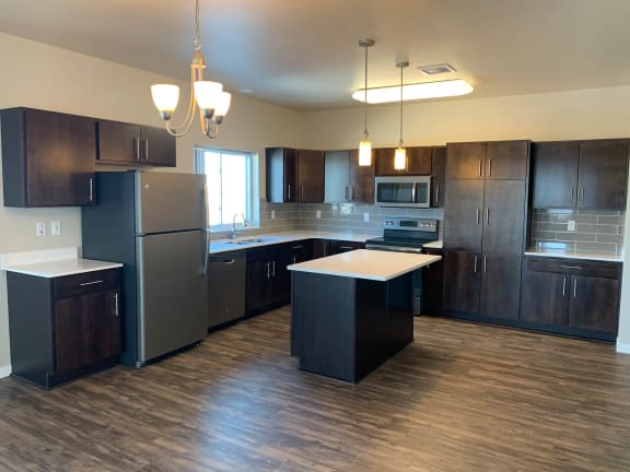 an empty kitchen with dark wood cabinets and stainless steel appliances
