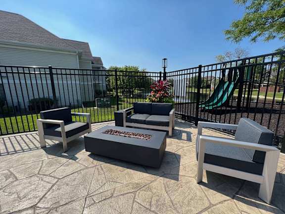 A set of four grey outdoor chairs are arranged on a patio.