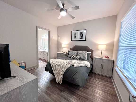 A bedroom with a bed, a television, and a ceiling fan.