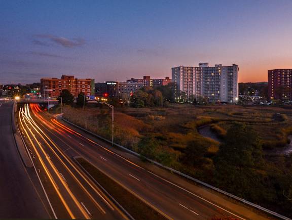 A highway with moving cars is shown at dusk.