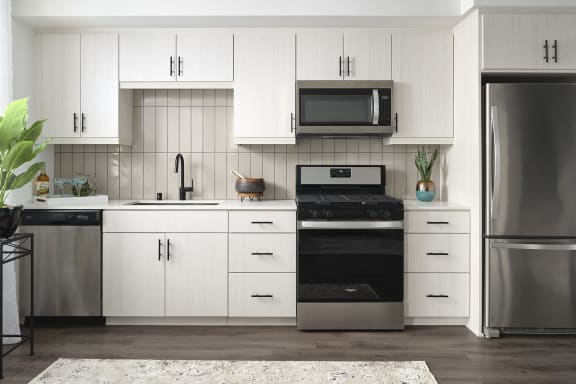 a white kitchen with stainless steel appliances and white cabinets