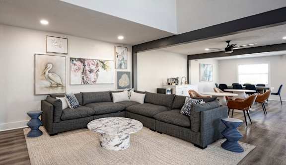 A living room with a grey sofa and a round marble table.