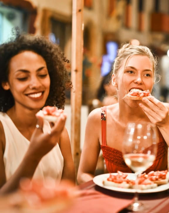 two women eating pizza at a restaurant