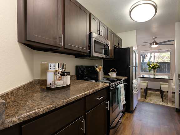 A kitchen with brown cabinets and a black refrigerator.