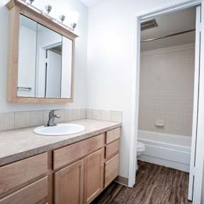 A bathroom with a sink, mirror, and wooden cabinets.