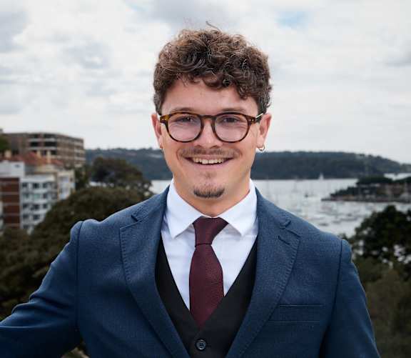 A man in a suit and tie standing in front of a body of water.
