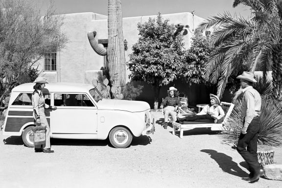 a group of men standing around a car in the desert