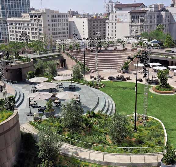 A green park area with a lot of trees and a stage.