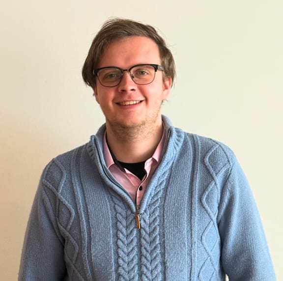 A man wearing glasses and a blue cardigan.