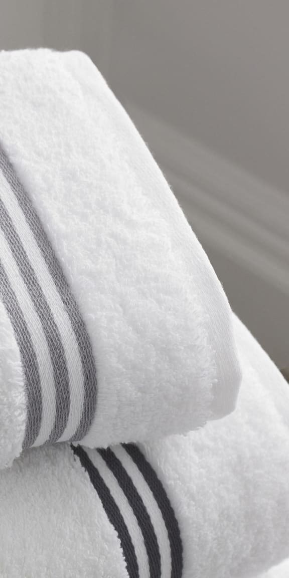 a white towel with black and white stripes on top of a bed