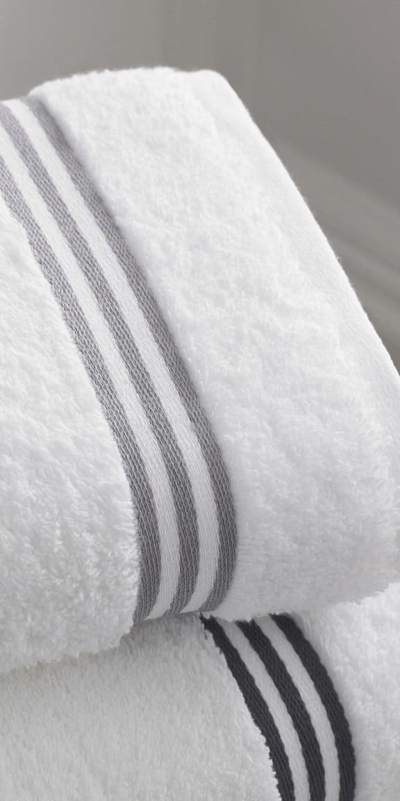 a white towel with black and white stripes on top of a bed