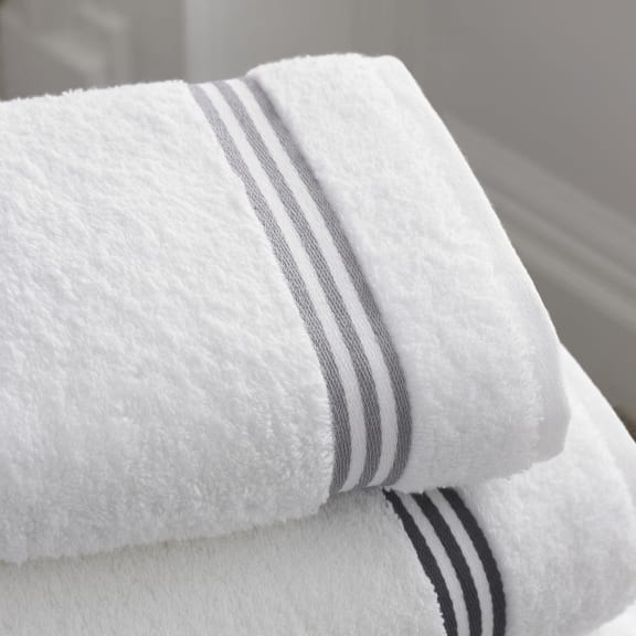 a white towel with black and white stripes on top of a bed
