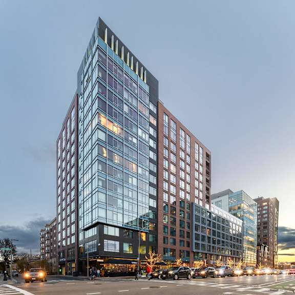 A modern glass building with a red brick facade stands tall in the city.