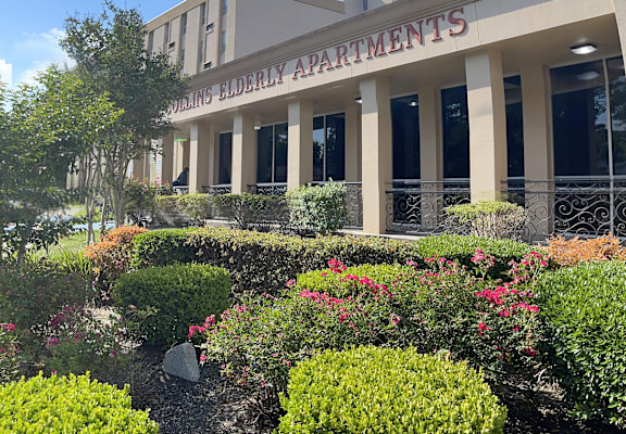 a picture of the front of the building with flowers and bushes in front of it