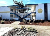 Thumbnail 2 of 8 - A white building with a blue roof and a sign that says "Tamarack 702" is shown.