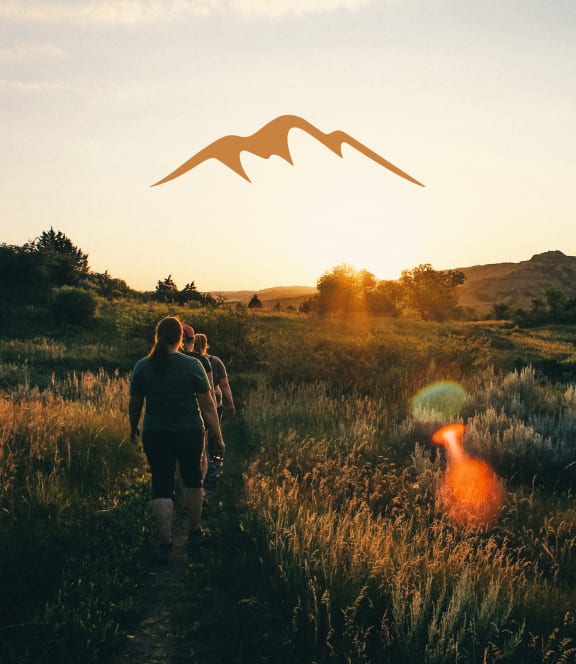 Group of Friends Walking Through Field Together During Sunset