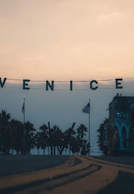 A street sign that reads "Venice" is strung up on a wire.