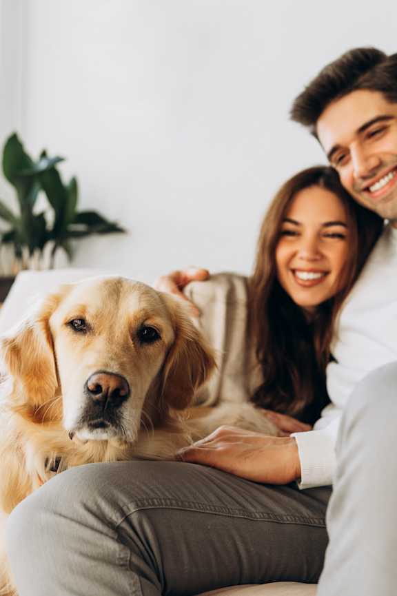 Man and Woman Smiling while Sitting on Couch with Dog