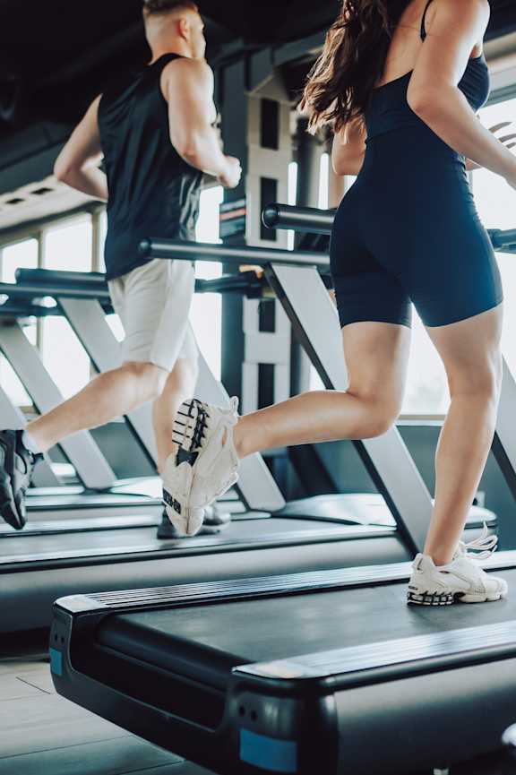 Man and Woman Running on Treadmills in Gym