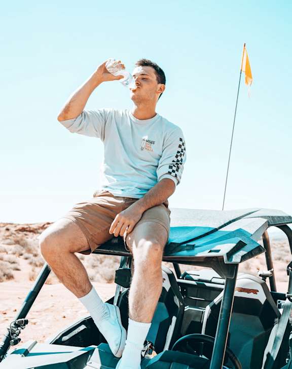 a man drinking water while sitting on a golf cart