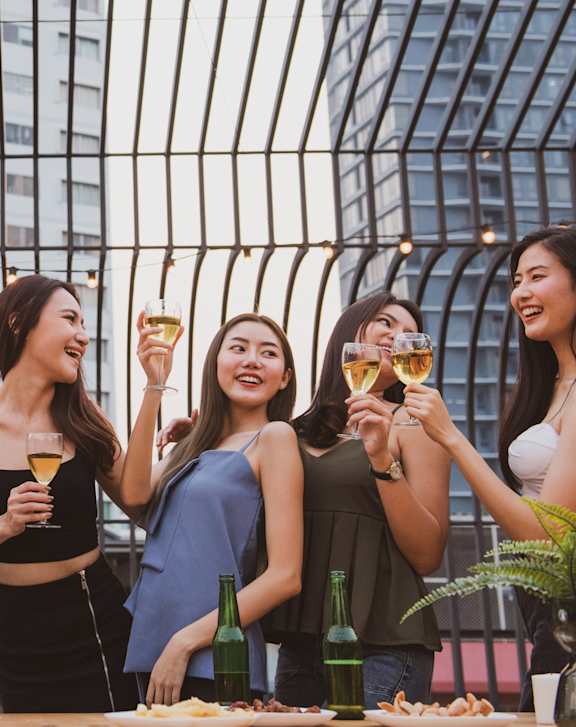 Four women toasting with glasses of wine at a table.