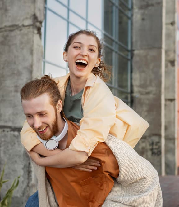 A man is carrying a woman on his back in an urban setting.