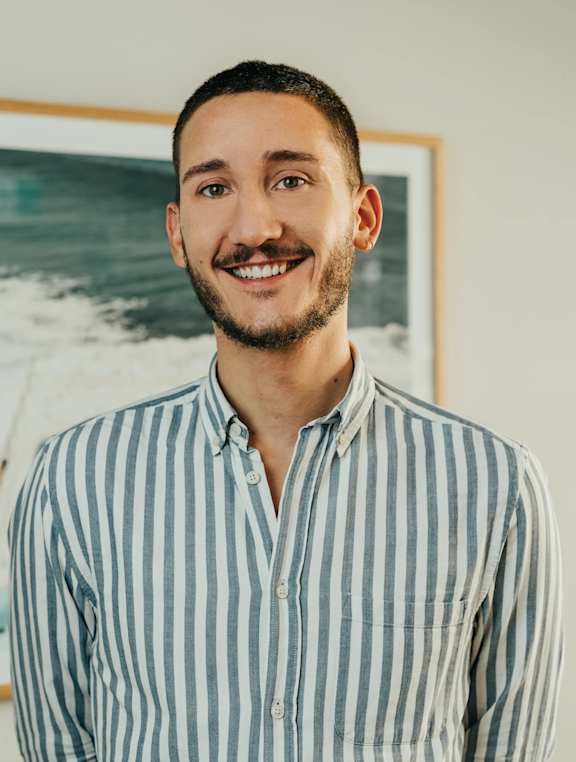 A man with a beard and short hair is wearing a striped shirt.