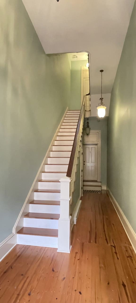 a staircase in a house with green walls and wood floors
