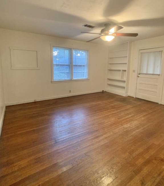 an empty living room with wooden floors and a ceiling fan