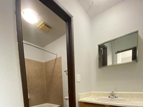 A bathroom with a wooden cabinet and a white sink.