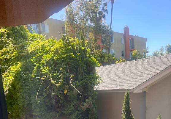 A balcony with a metal railing and a view of a building and trees.