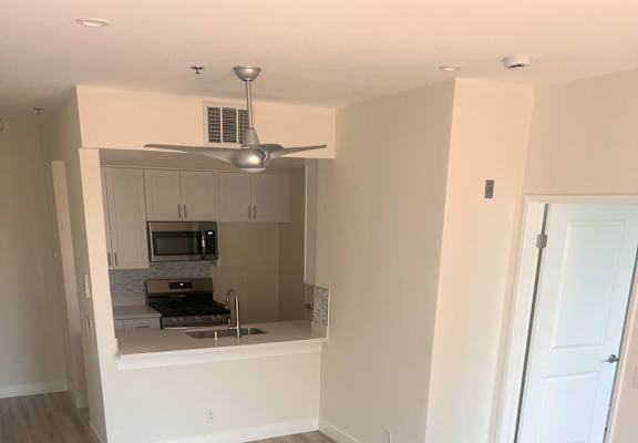 A room with a kitchenette and a fan.