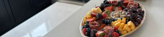 A white counter with a plate of fruit and three boxes of cookies.
