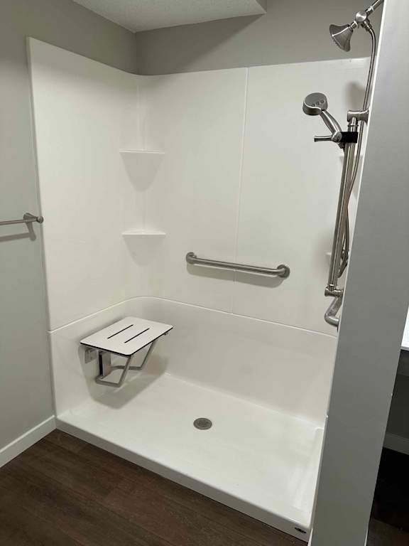 A white shower stall with a bench and a drain.