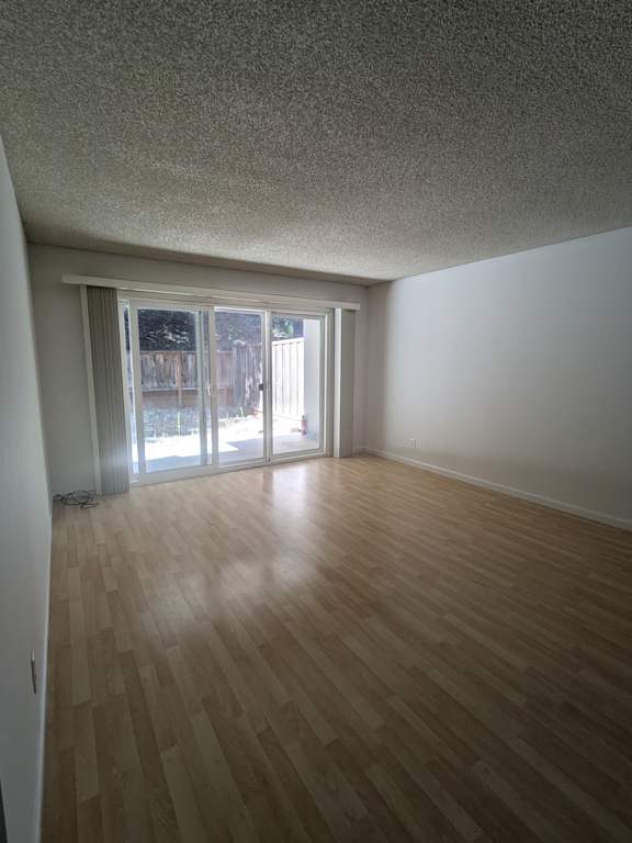 an empty living room with wood floors and a sliding glass door