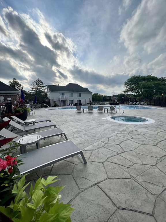 A pool area with a hot tub and lounge chairs.
