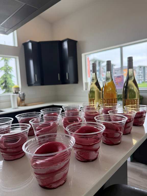 A row of wine glasses are lined up on a shelf.