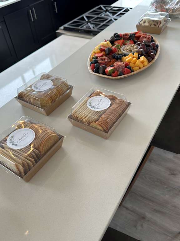 A white counter with a plate of fruit and three boxes of cookies.
