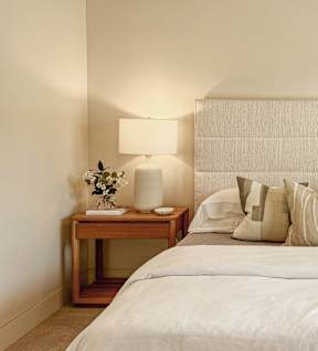 A bedroom with a bed, nightstand, and lamp.