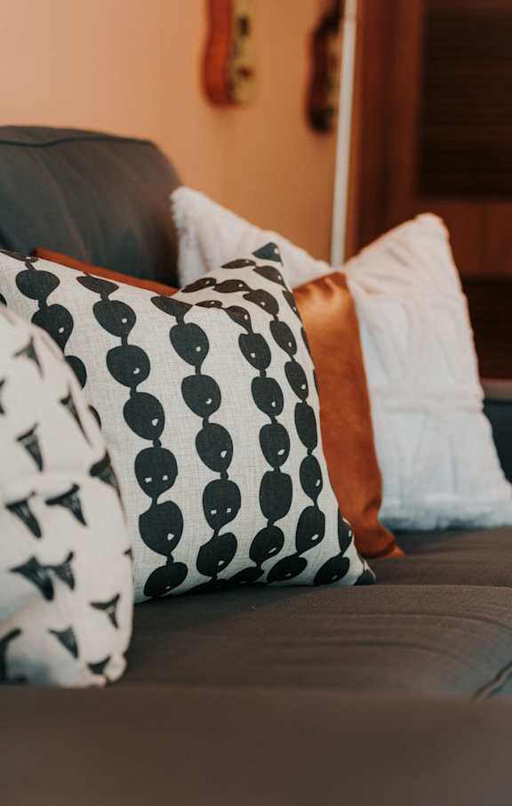 A couch with a black and white pillow with a pattern of circles and triangles.