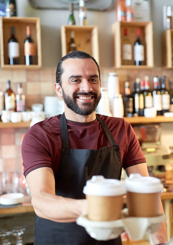 a man in an apron holding a stack of coffee cups
